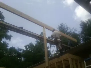 Carpenter setting a ridge beam over a new addition frame — Ice Dam Removal by Roofing Brothers in West Newton